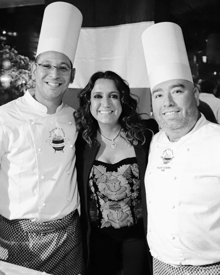 Verónica junto a los dos chefs del restaurante, delante de la bandera italiana